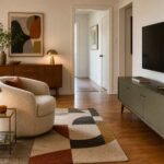 Small mid-century modern living room with a compact swivel chair, low green media cabinet, warm wood sideboard, brass lamp, and a clear walking path